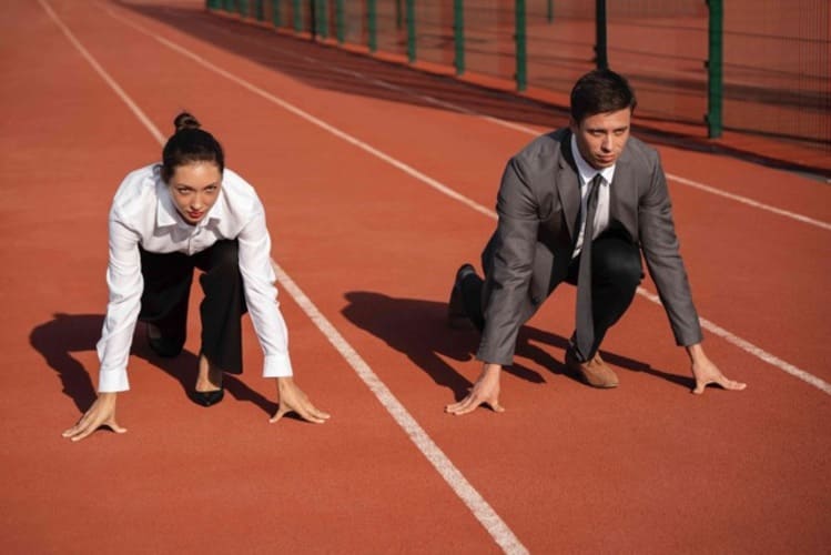 Cadres dirigeants en costume en position de départ sur une piste d’athlétisme, illustration de la pression de performance professionnelle.