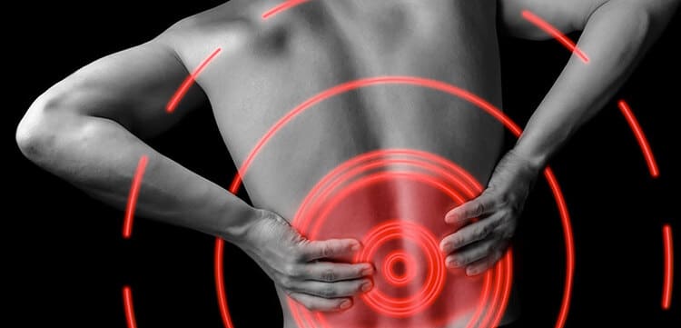 Homme souffrant de lombalgie chronique, les mains dans le bas du dos avec une zone de douleur mise en évidence en rouge