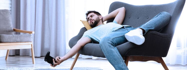 Homme allongé sur un canapé illustrant les effets de la sédentarité et du manque d'activité physique