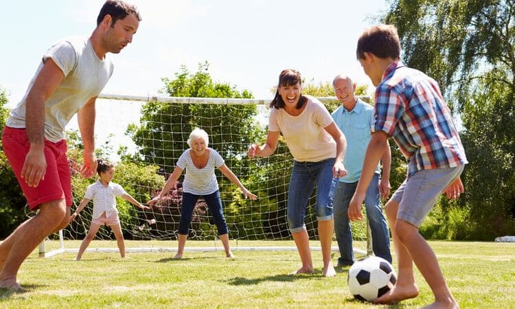 Sport et équilibre de vie : famille multigénérationnelle jouant au football dans le jardin