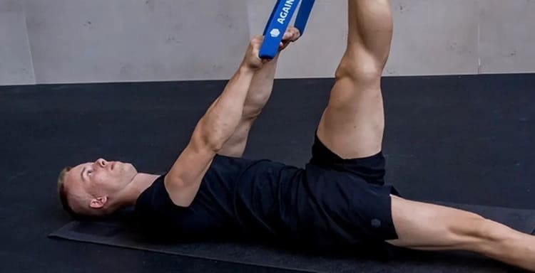 Homme allongé réalisant un étirement des ischio-jambiers à l'aide d'un élastique de résistance, technique de stretching actif