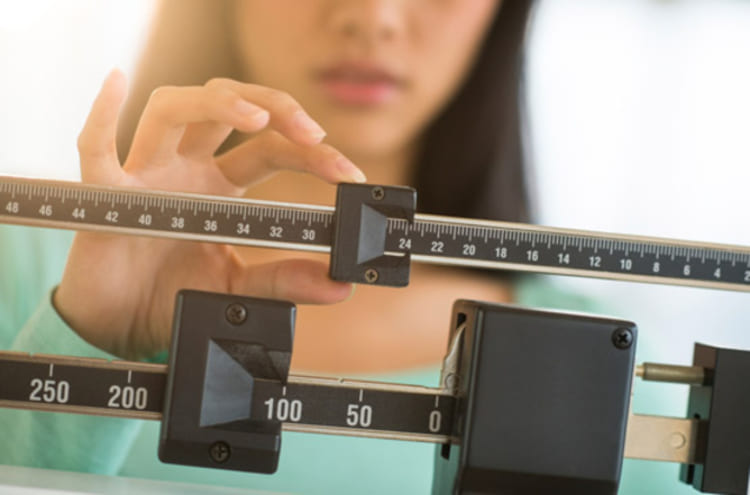 Poids de forme et santé articulaire : femme réglant une balance mécanique pour suivre l'évolution de son poids