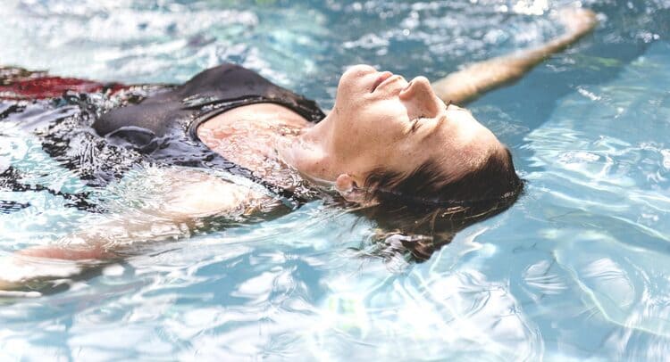 Femme flottant et se détendant dans une piscine, illustrant les bienfaits de la natation pour la gestion du stress par le sport à Paris